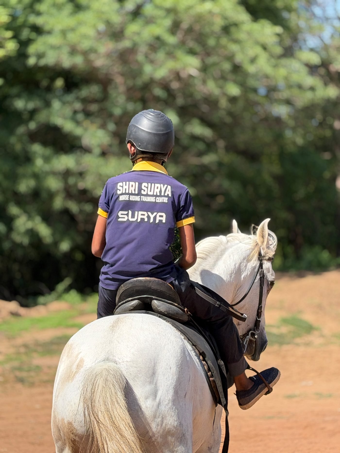 Young rider in Save Native Horses Trust jersey riding a grey horse